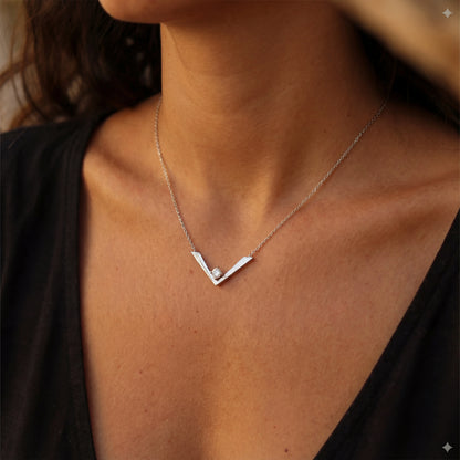 שרשרת GAYA NECKLACE יוקרתית מבית Lidi, עשויה סטיינלס סטיל עם תליון 'וי' משובץ זרקון נוצץ, על צוואר אישה.