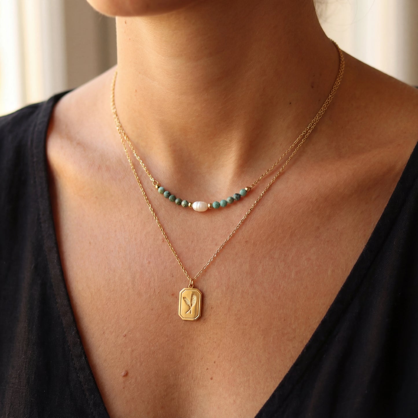 שרשרת LUNARIA NACKLACE כפולה יוקרתית מבית Lidi עם חרוזי טורקיז אפריקאי ותליון מעוטר על רקע לבן, מציגה את יופייה העדין והמרהיב.